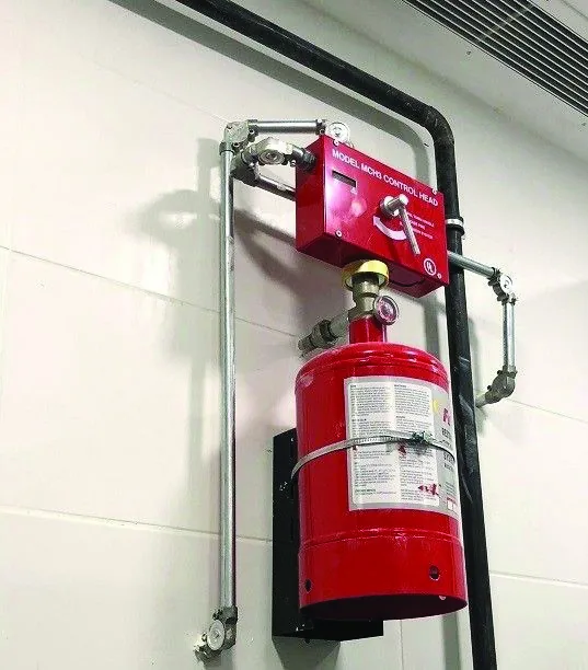 Wall-mounted wet chemical fire suppression cylinder installed in a commercial kitchen